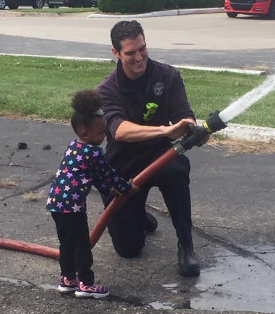 Adult and child holding a fire hose with water spraying out