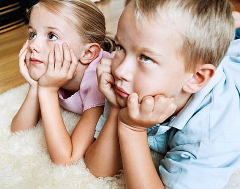 Two children lying on a rug with chins resting on hands