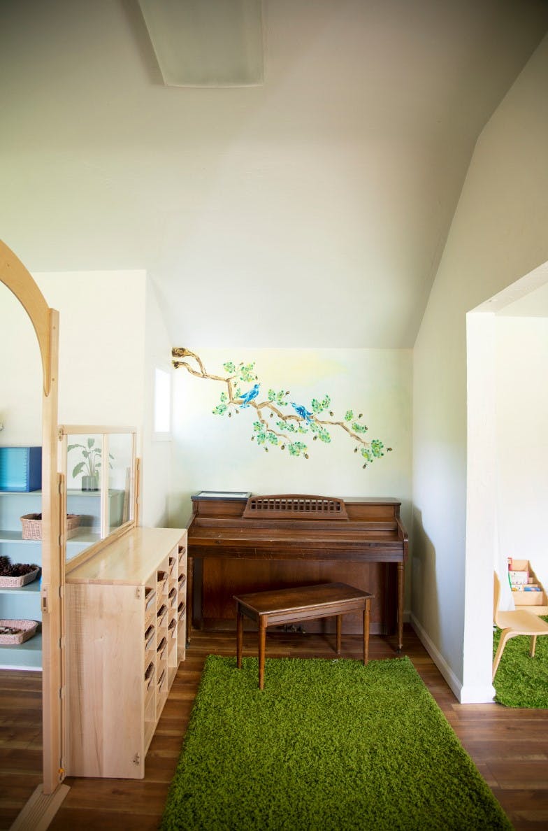 Piano with a green rug and a wall decal of birds on a branch