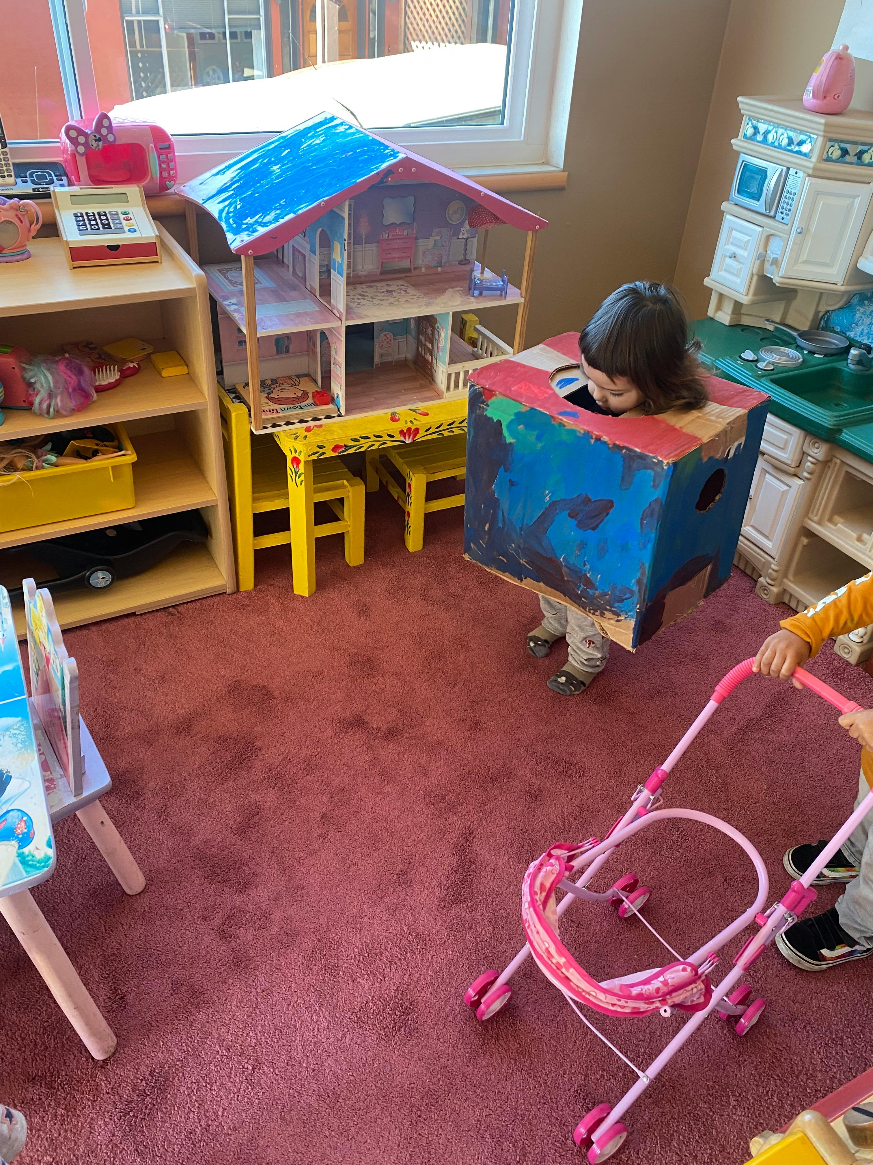 Child wearing a painted box costume, another child pushing a toy stroller