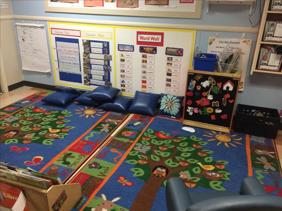 Classroom with a colorful rug, blue floor cushions, and a word wall