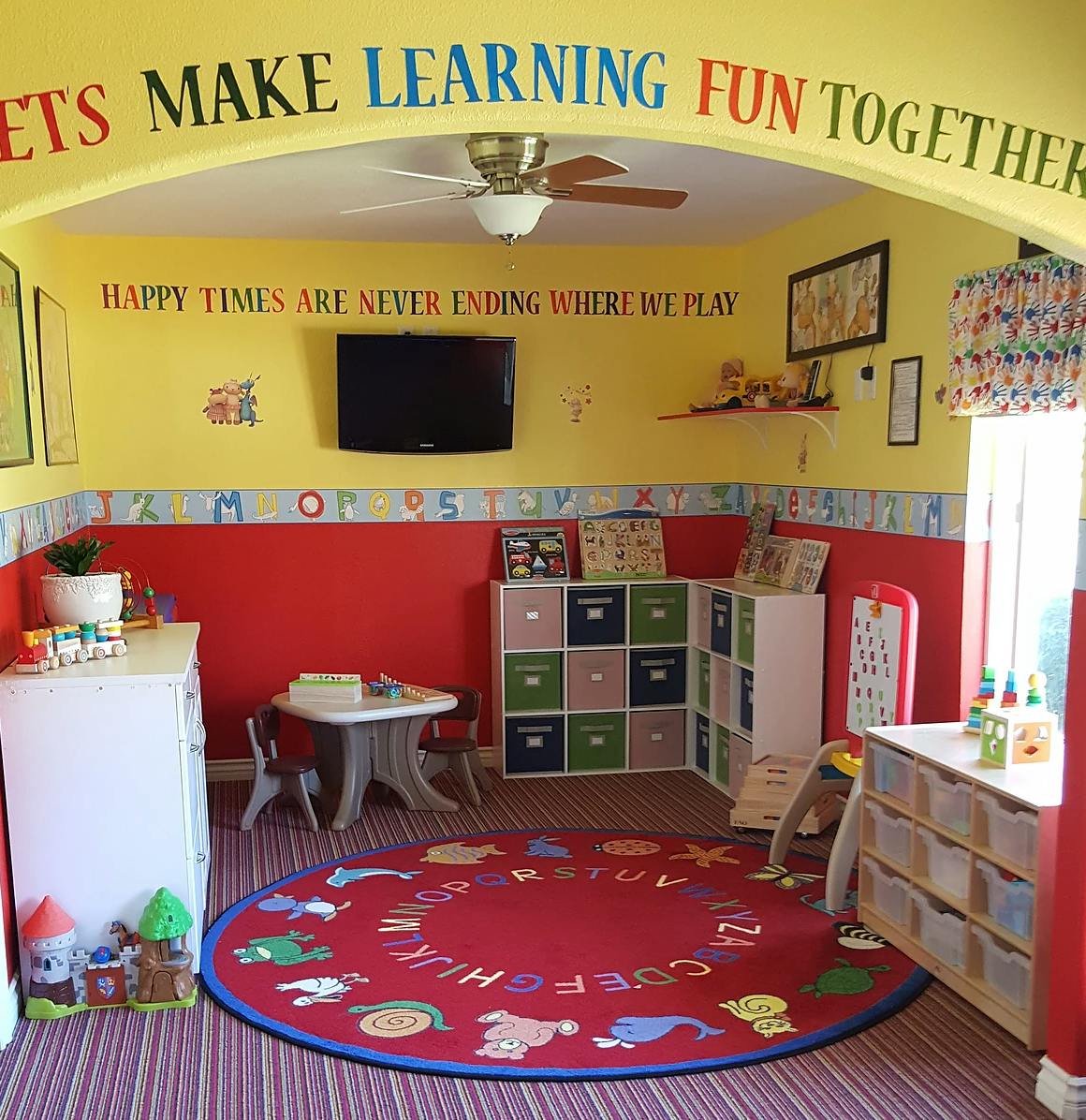 Playroom with red and yellow walls, a red circular rug, and toy storage