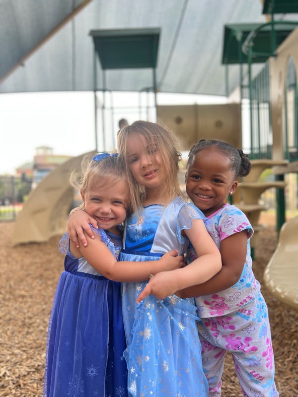 Three children hugging each other on a playground