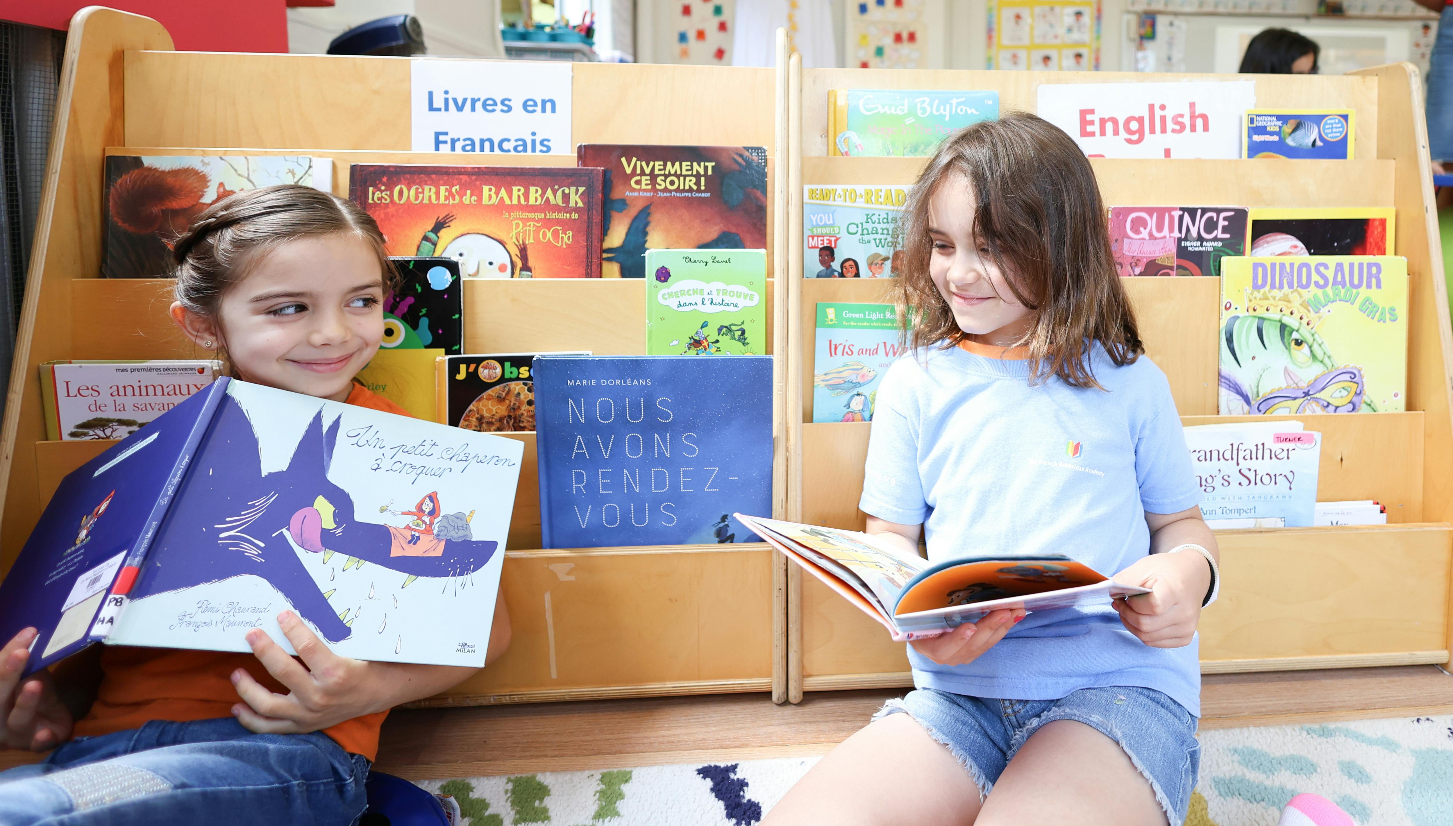 Two children reading books in front of bookshelves