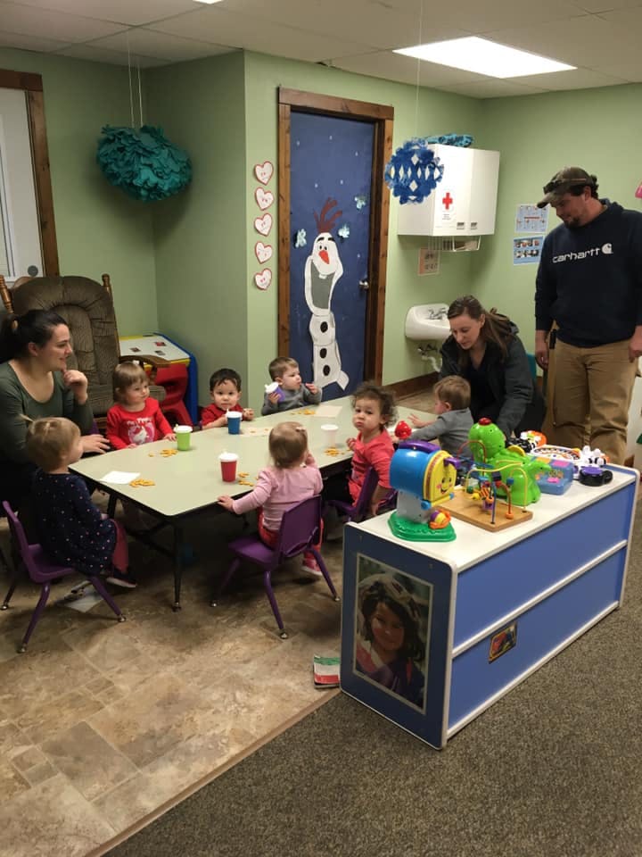 Adults and children gathered around a table in a classroom