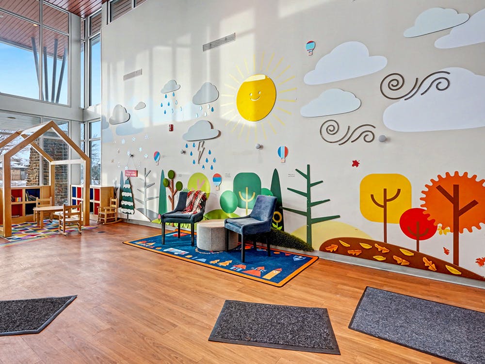 Children's room with house-shaped play structure and wall mural depicting nature