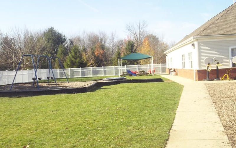 Playground with swings, a picnic table under a canopy, and a building