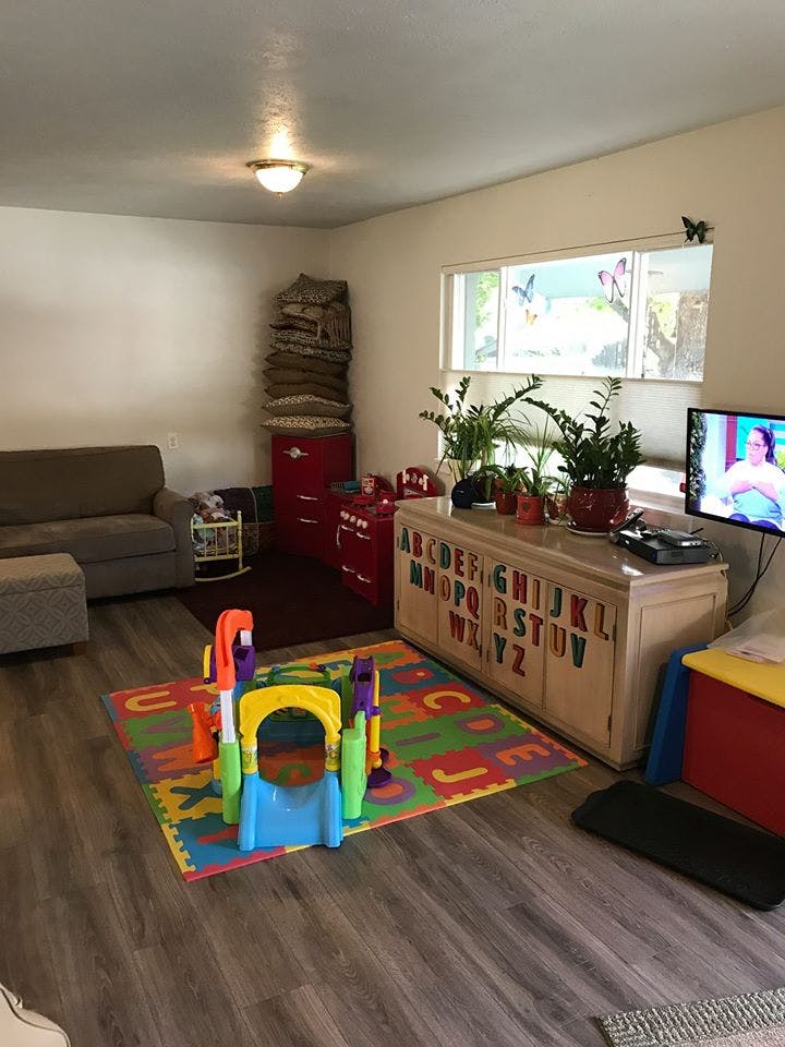 Living room with a sofa, TV, and a colorful play mat with a small slide