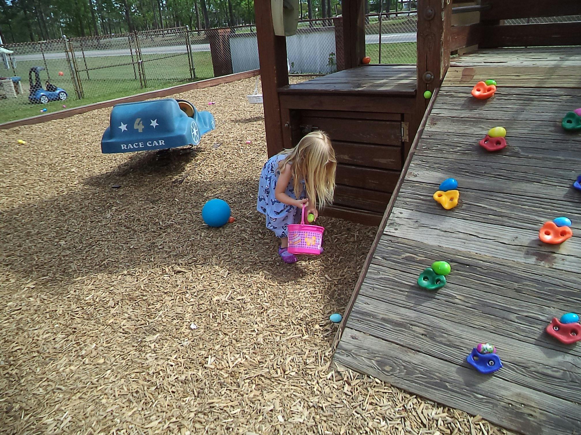 Child holding a pink bucket on a playground