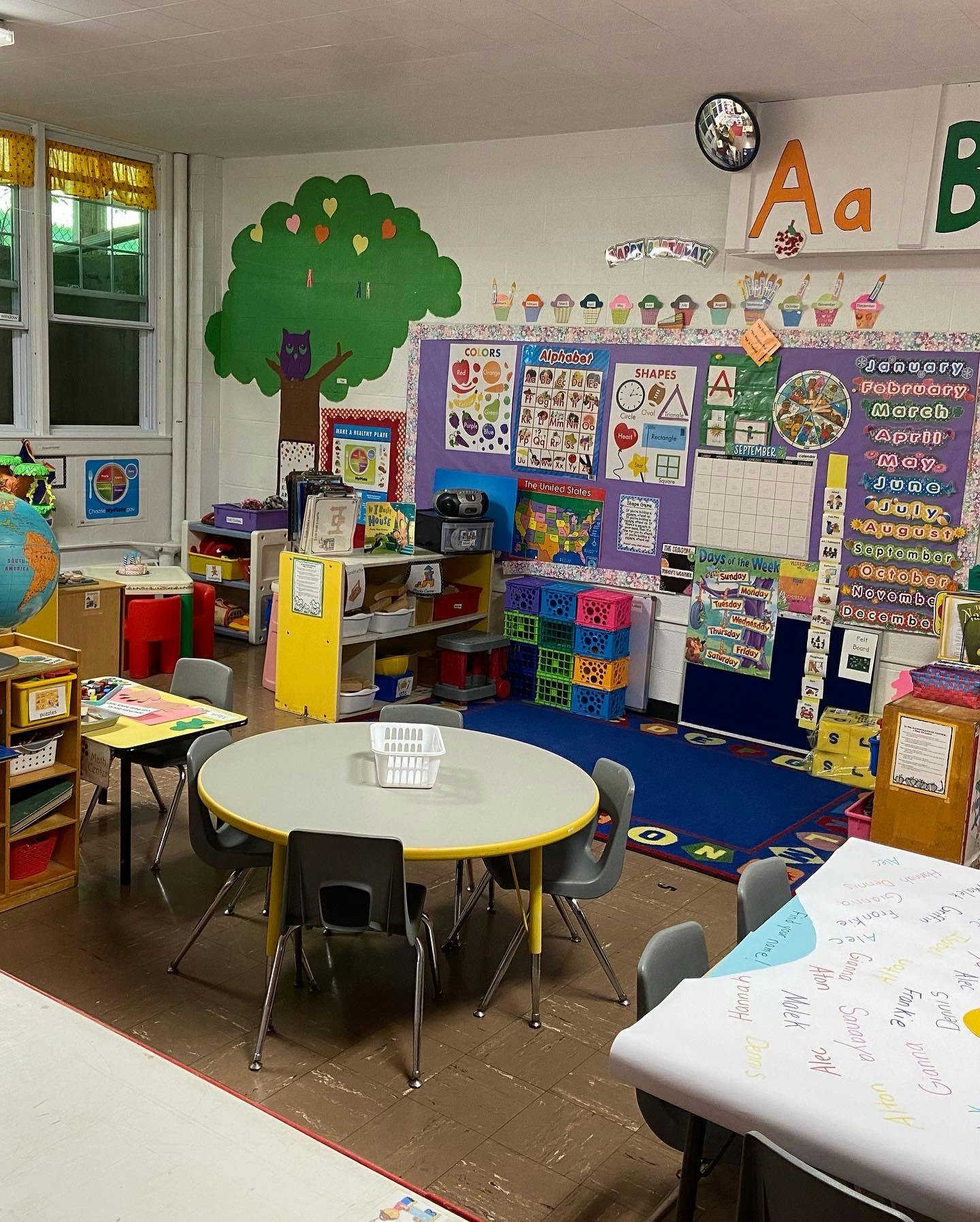 Classroom with tables, chairs, and educational decorations on the walls