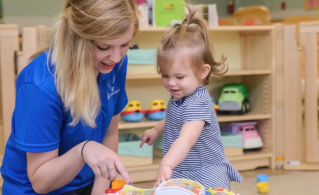 Adult and child playing with toys in a classroom