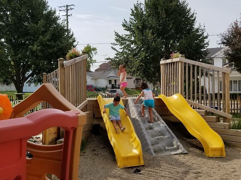 Children playing on a playground slide and climbing structure