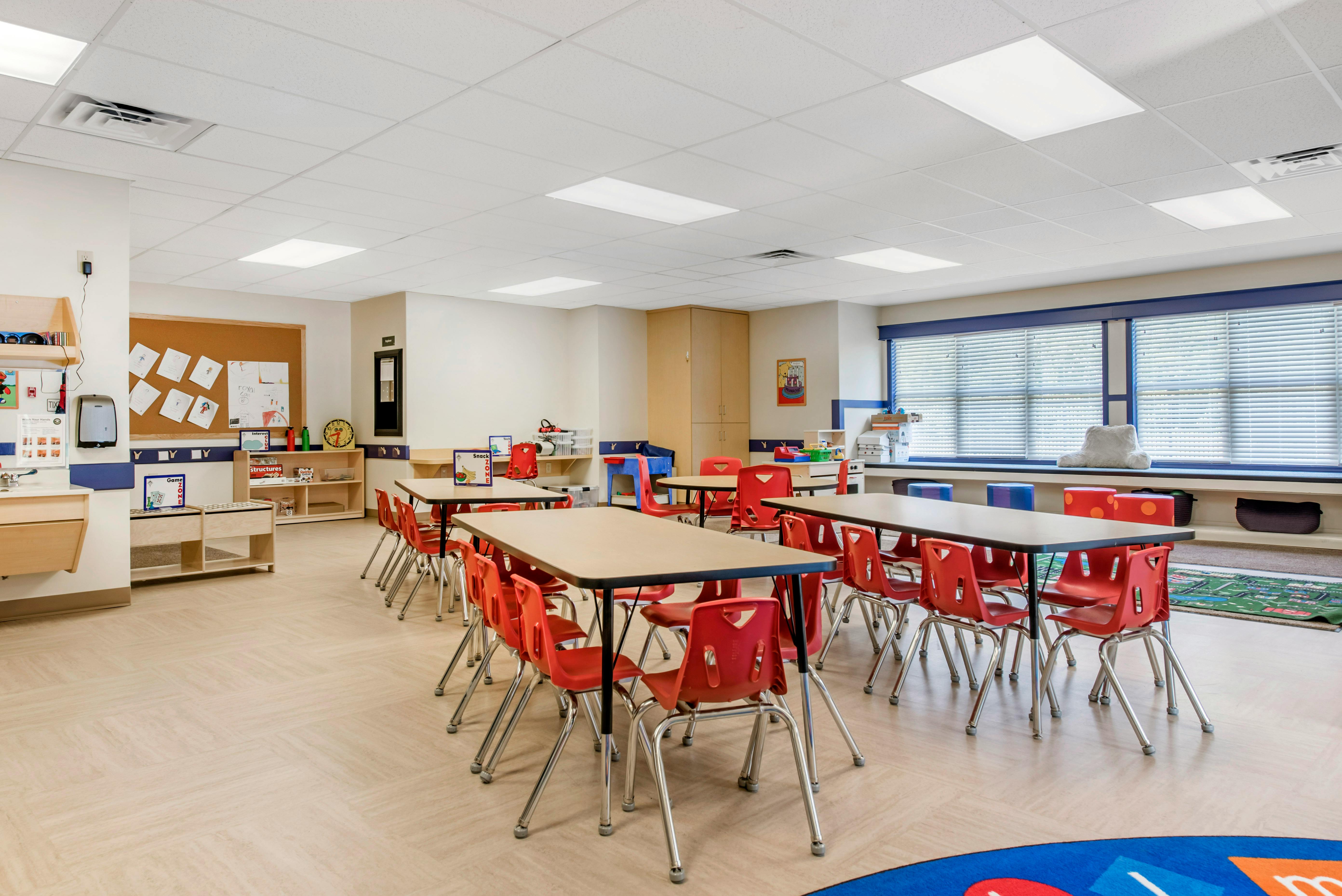 Empty classroom with small tables and red chairs