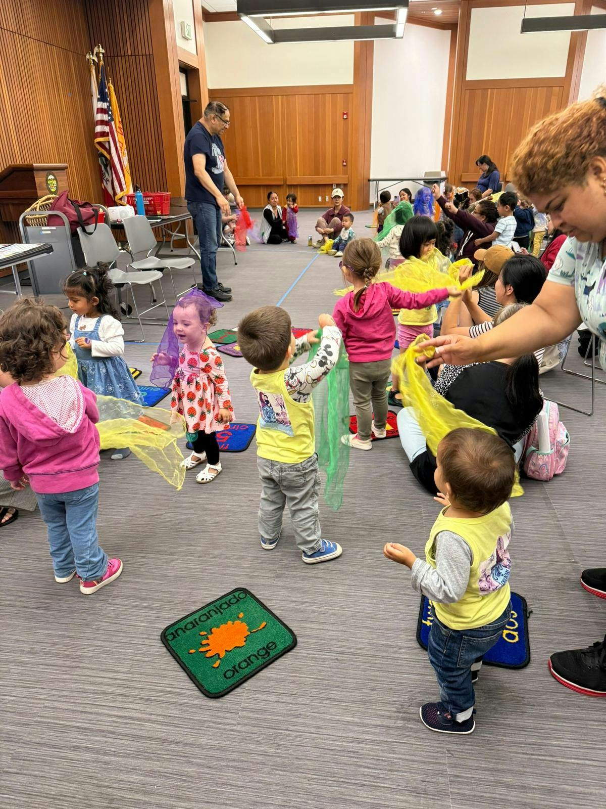 Children dancing with scarves in a classroom with adults