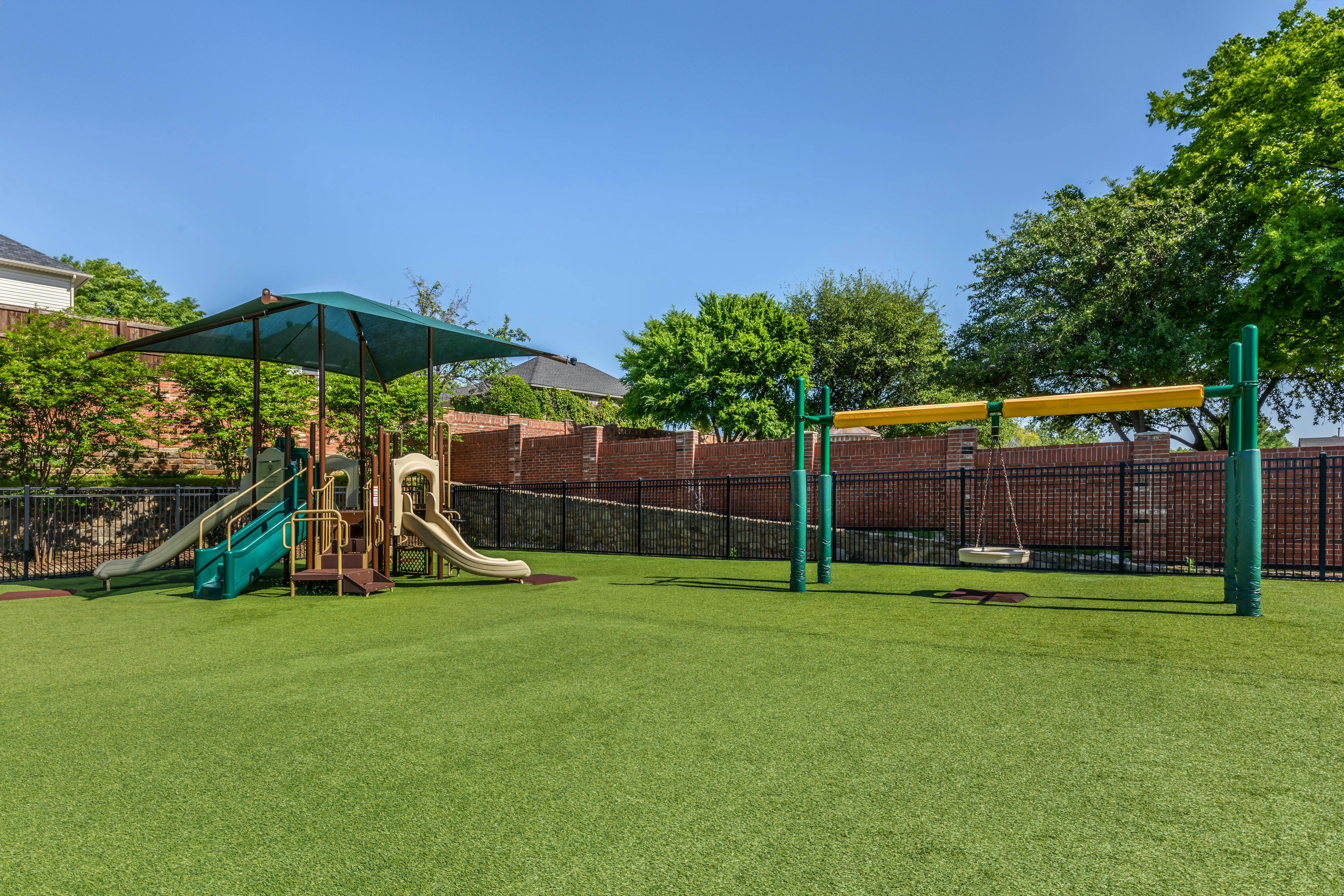 Empty playground with artificial turf, slides, and a swing set