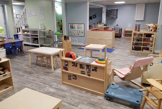 Playroom with child-sized tables, chairs, and shelves with toys