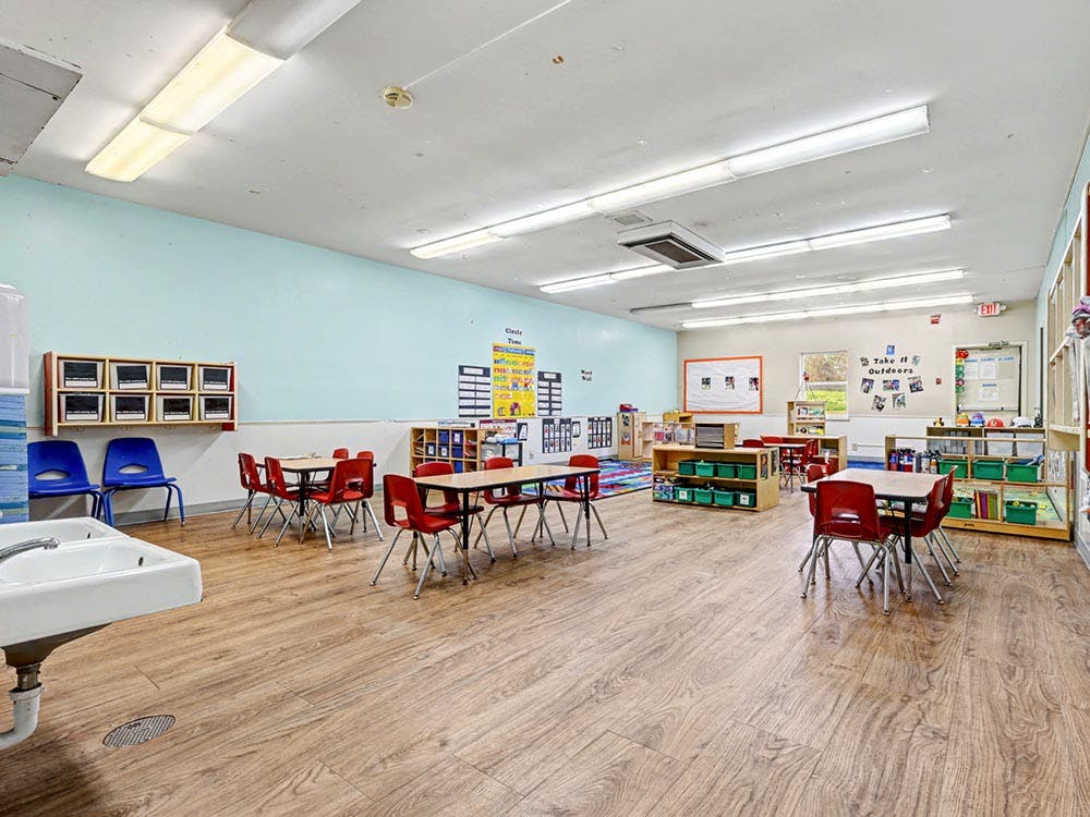 Classroom with tables and chairs, shelves, and a sink
