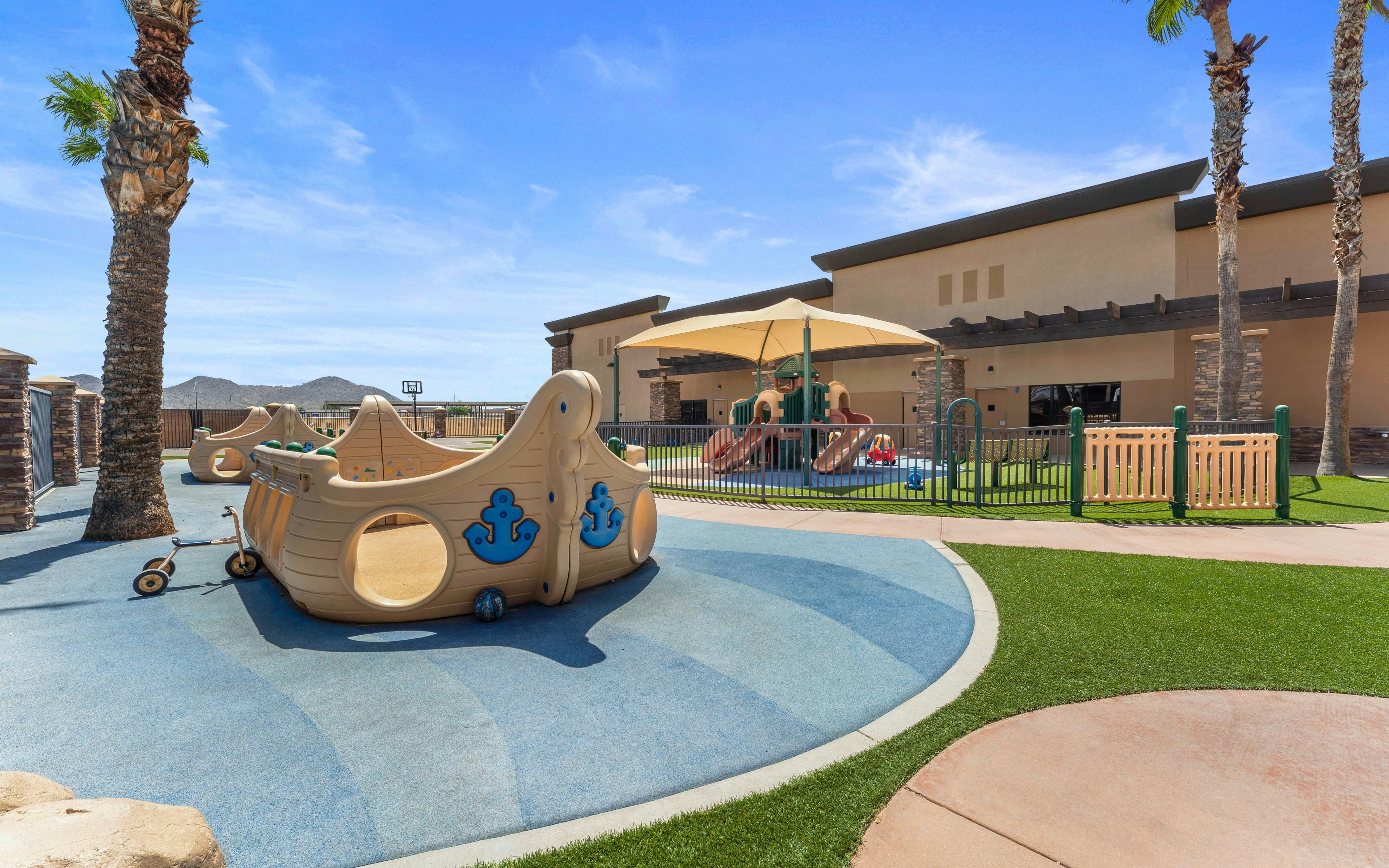Outdoor playground area with various play structures and palm trees
