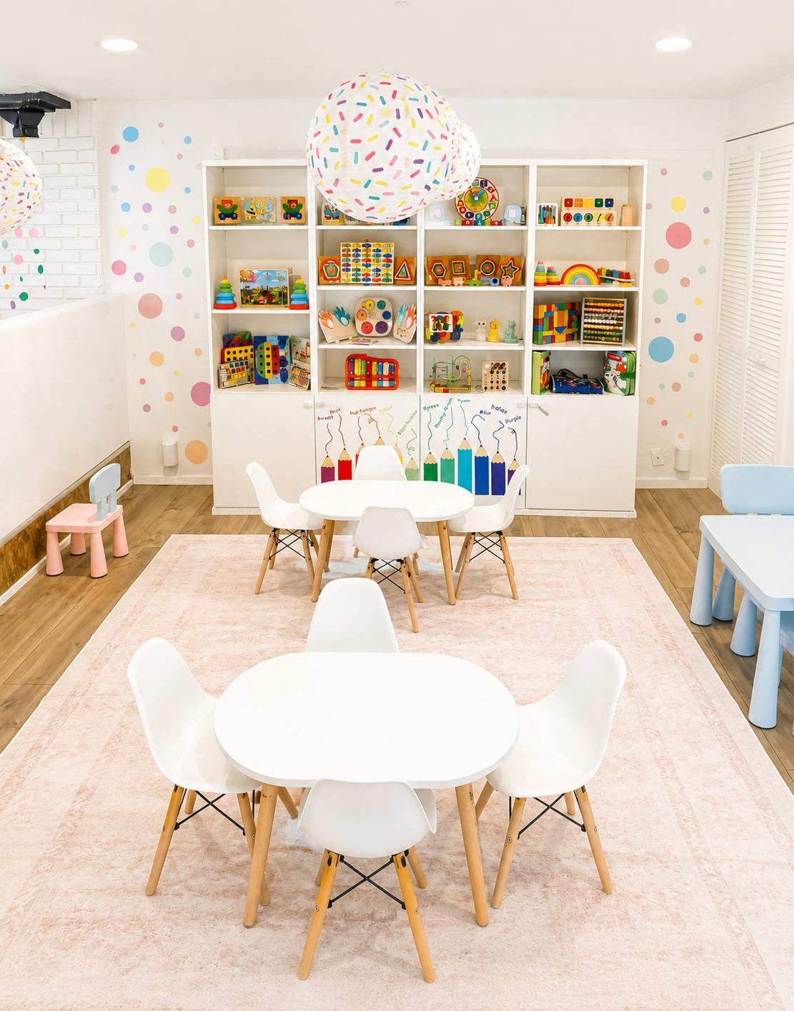 Childcare room with white tables, chairs, and shelves of educational toys