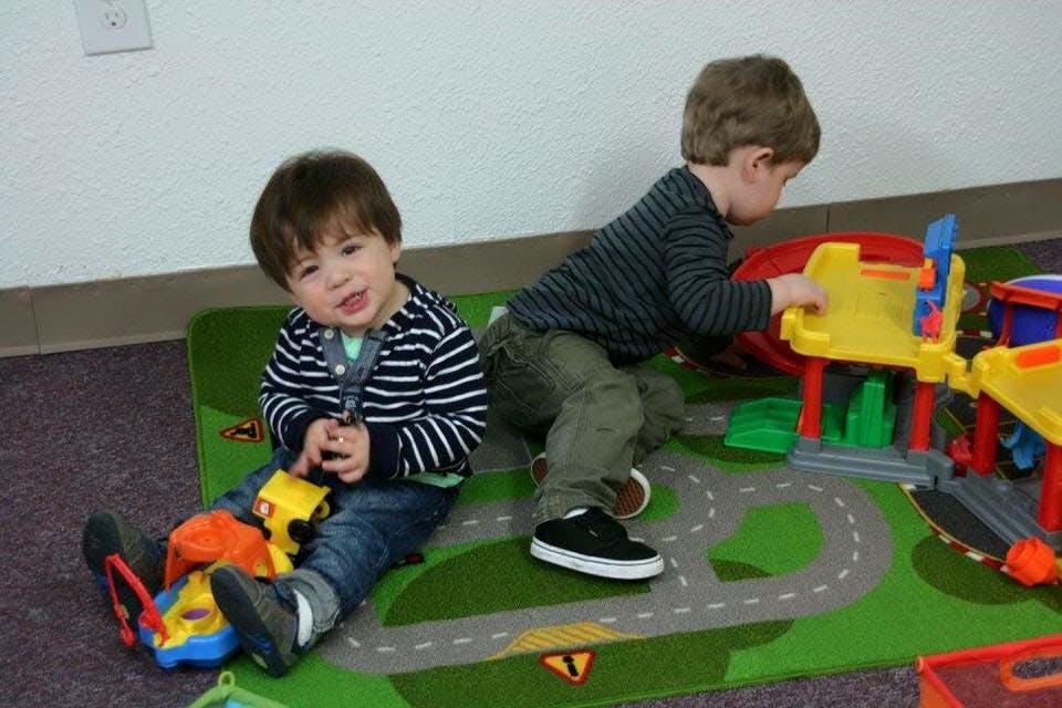 Two children playing with toys on a road-themed rug