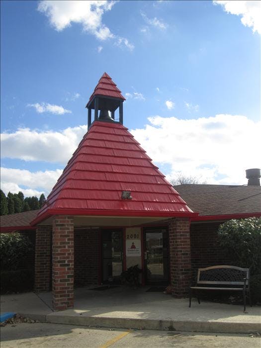 Building entrance with a red roof, brick columns, and bell tower