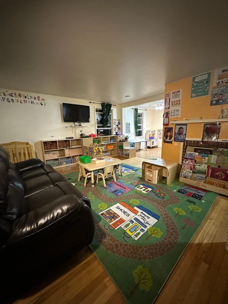 Playroom with a large rug, small tables, and a black sofa