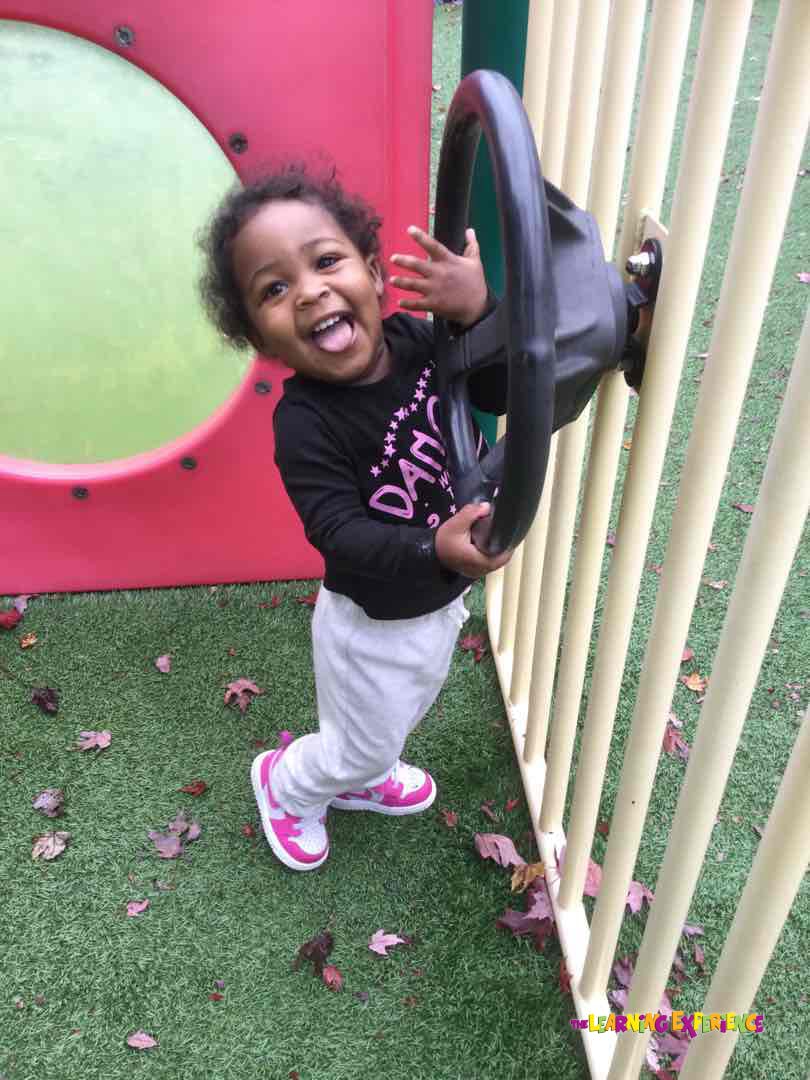 Child playing with a steering wheel toy on a playground