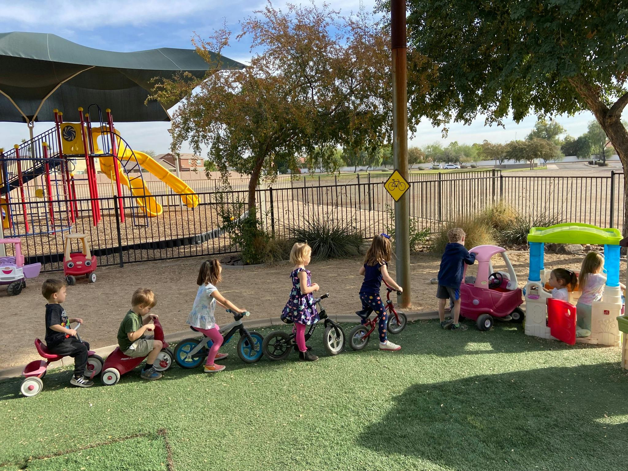 Children playing with ride-on toys and bicycles on a playground
