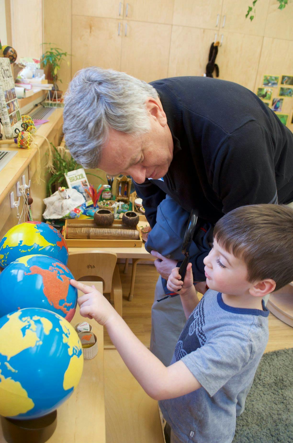 Adult and child looking at globes, child pointing at one