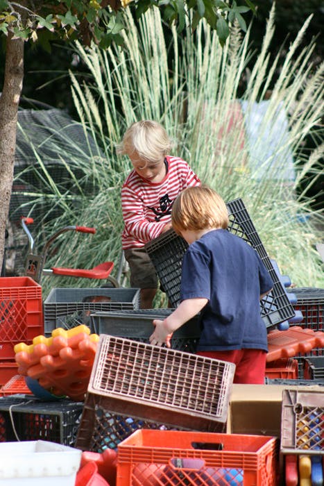 Two children playing with plastic crates outdoors