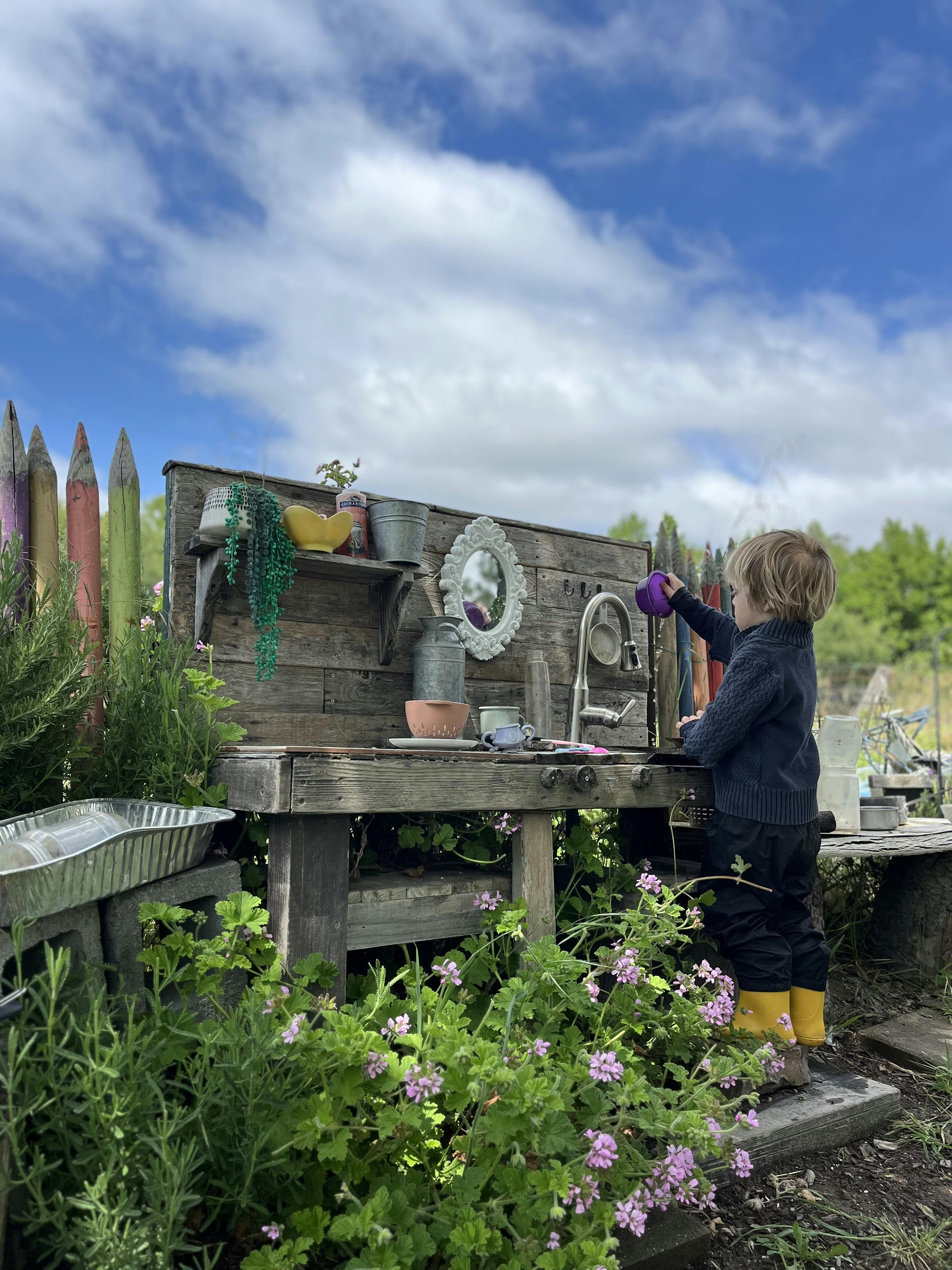 Child playing at an outdoor mud kitchen
