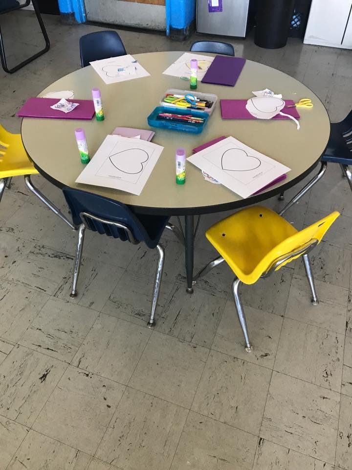 Round table with heart cutouts, glue sticks, and art supplies