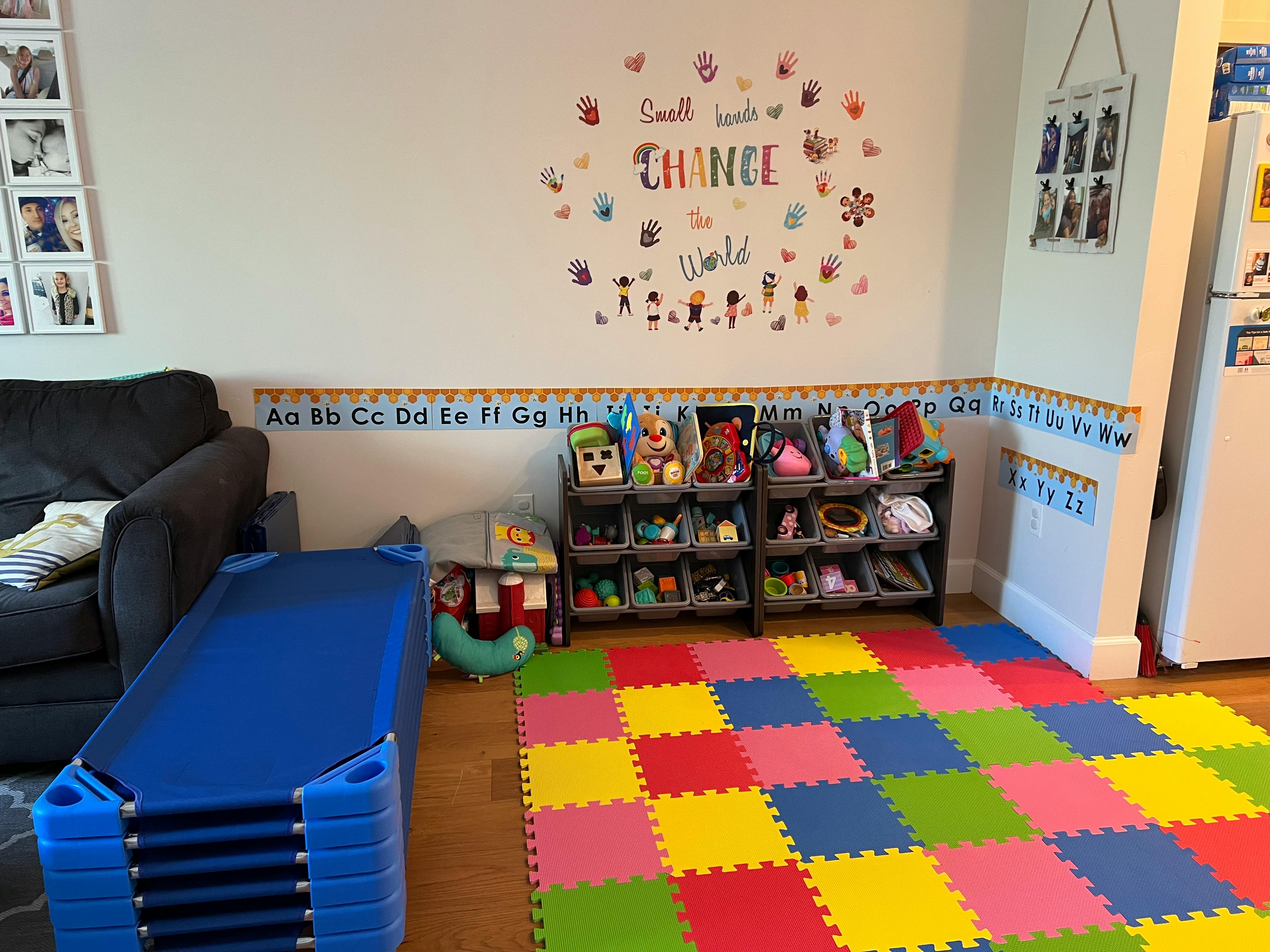Playroom with colorful floor mats, toy shelves, and stacked cots