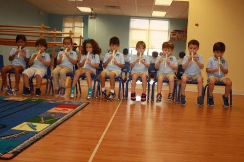 Children sitting in chairs playing recorders in a classroom