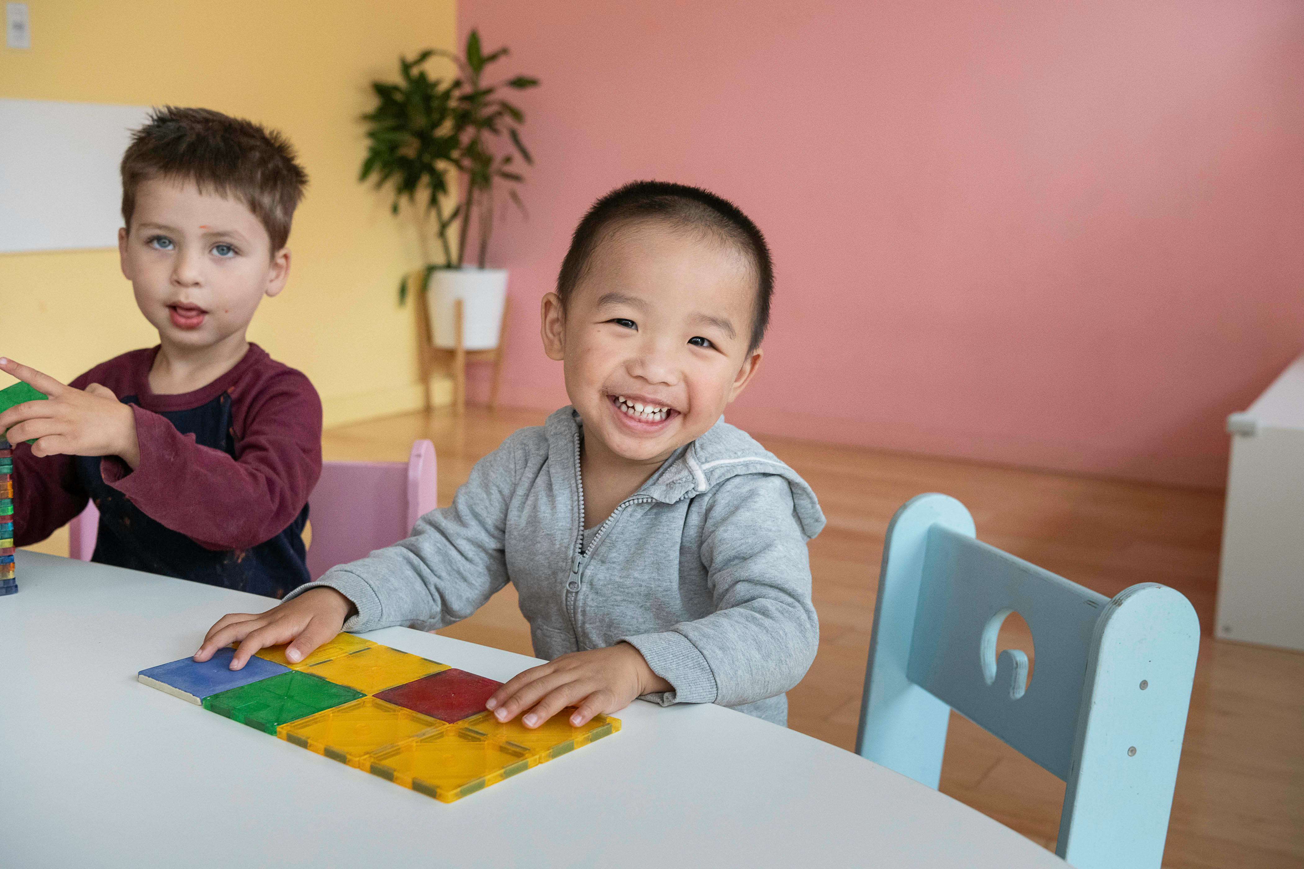 Two children at a table, one smiling at the camera