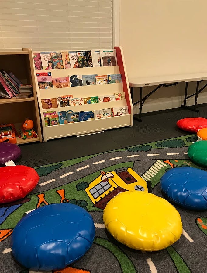 Children's book display and colorful floor cushions on a play rug