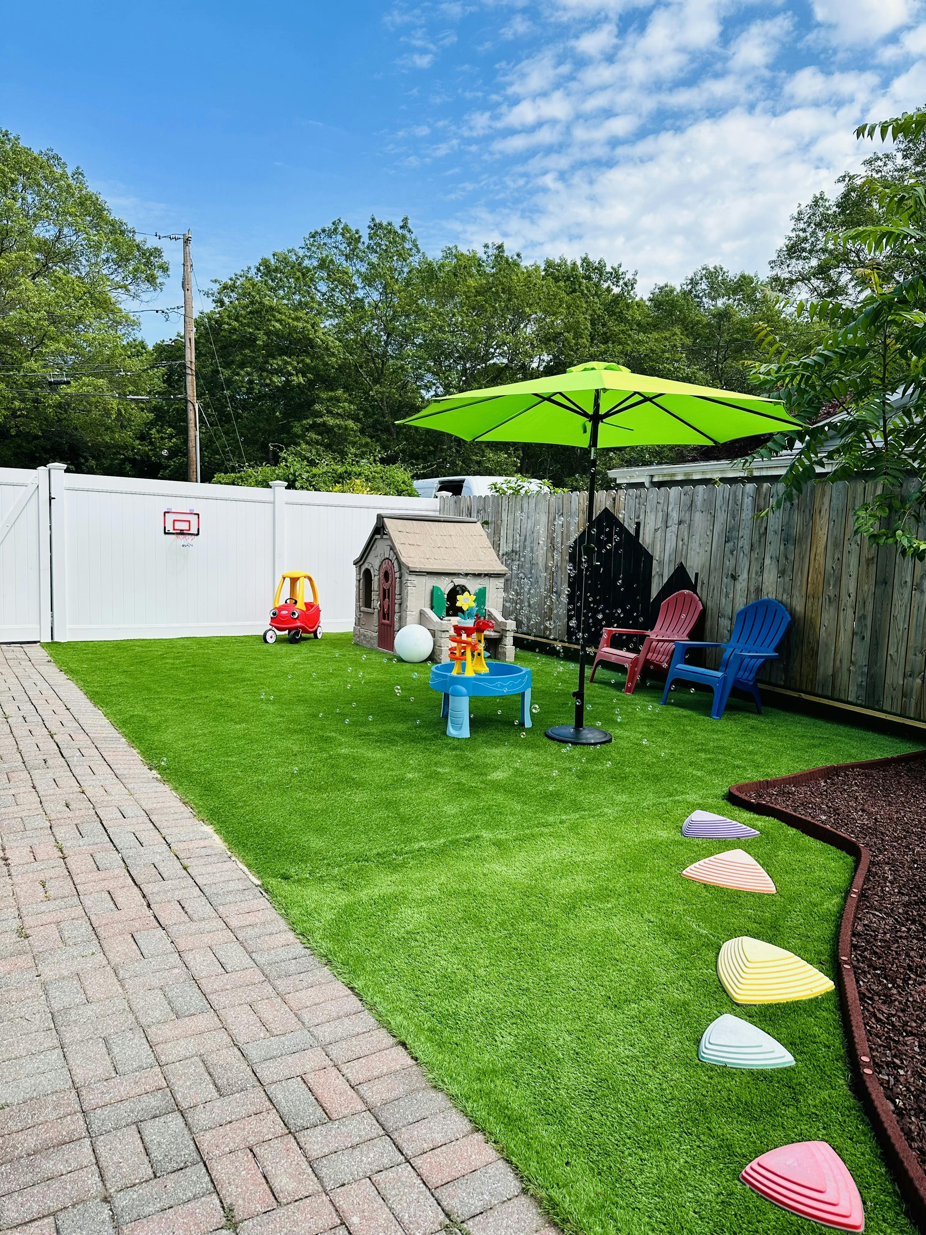 Outdoor play area with artificial grass, playhouse, and green umbrella
