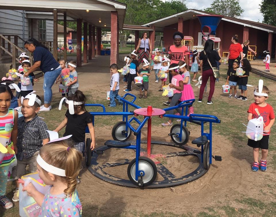People and children gathered outdoors around a playground merry-go-round
