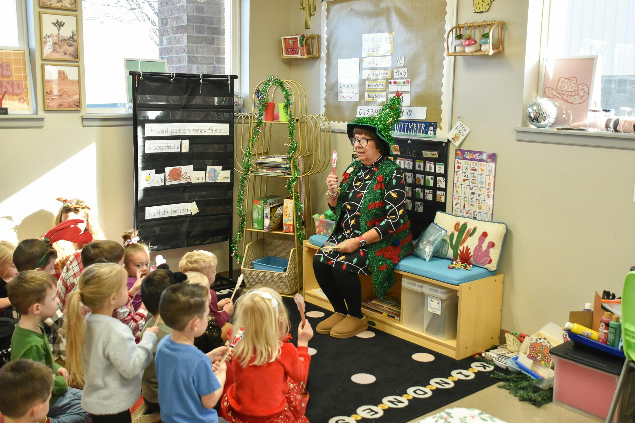 Adult in a classroom sitting with many children sitting on the floor around them