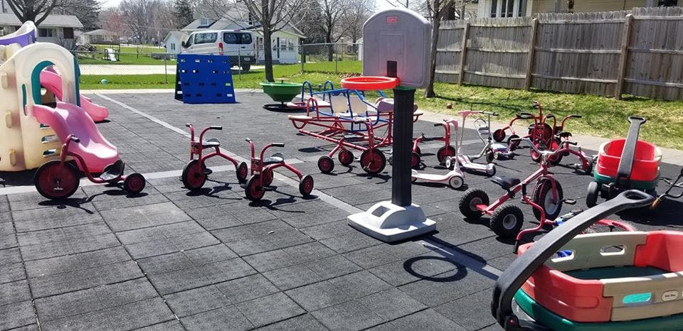 Playground with tricycles, scooters, and a basketball hoop