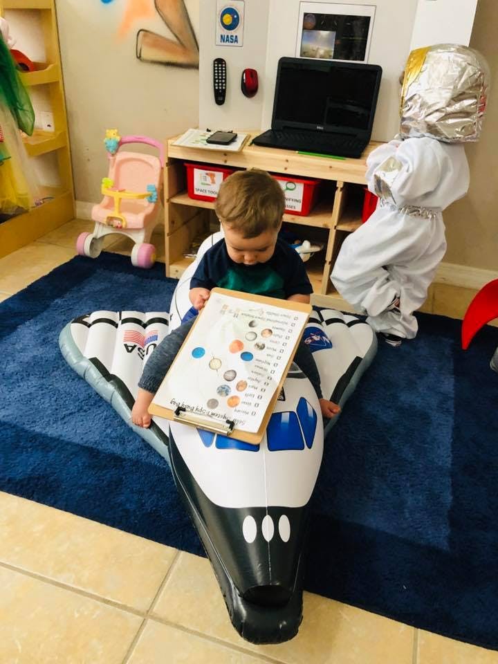 Child sitting on an inflatable space shuttle holding a clipboard