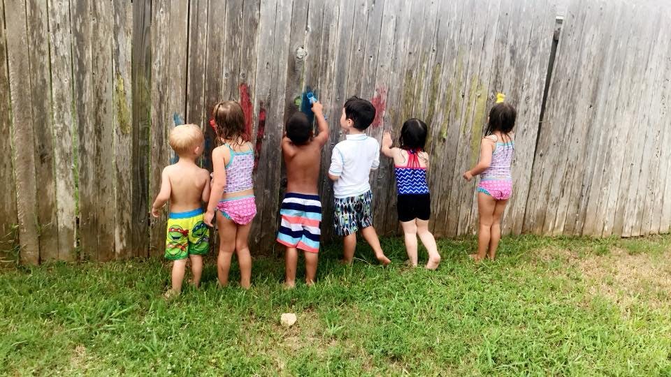 Children painting on a wooden fence