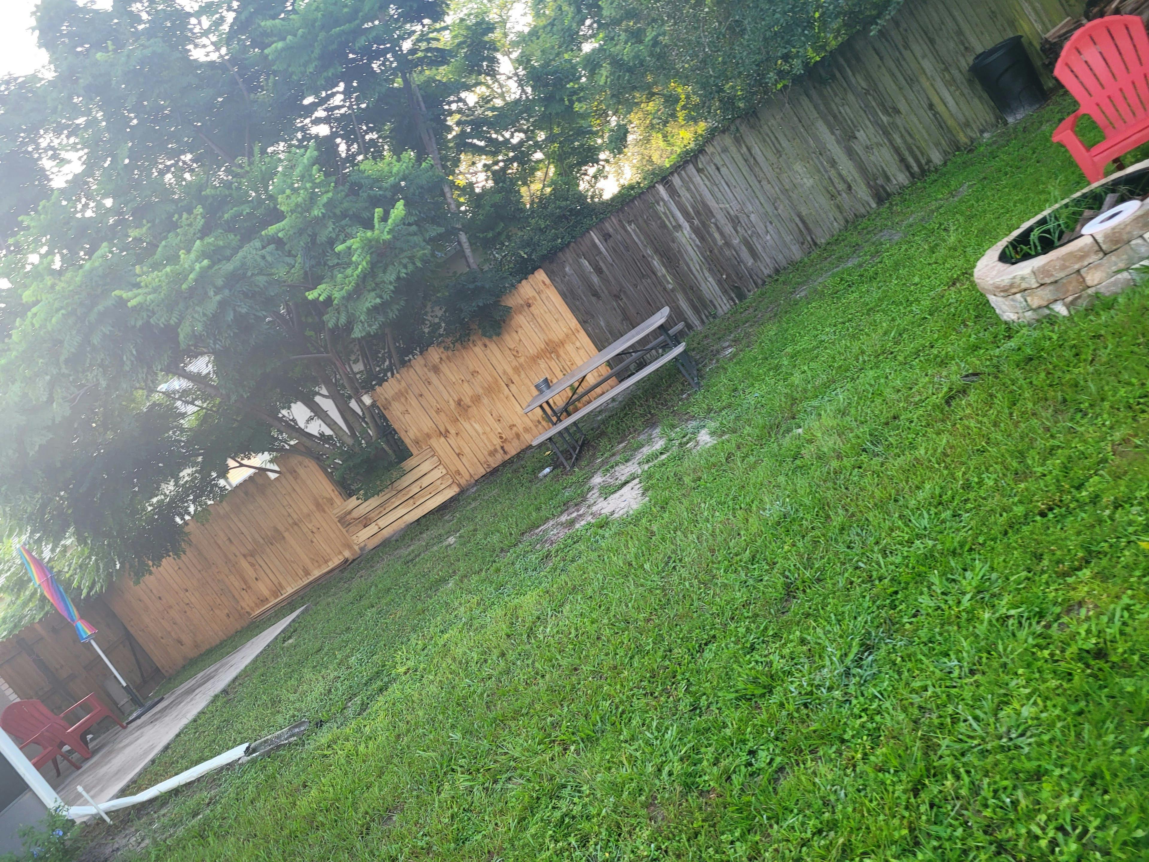 Grassy backyard with a wooden fence and a stone fire pit