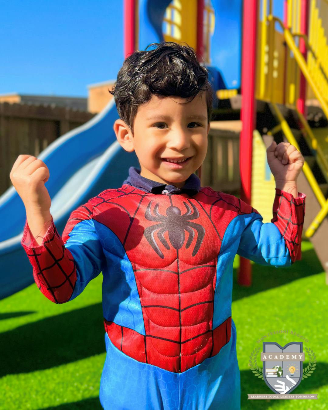 Child in a Spider-Man costume with fists raised on a playground
