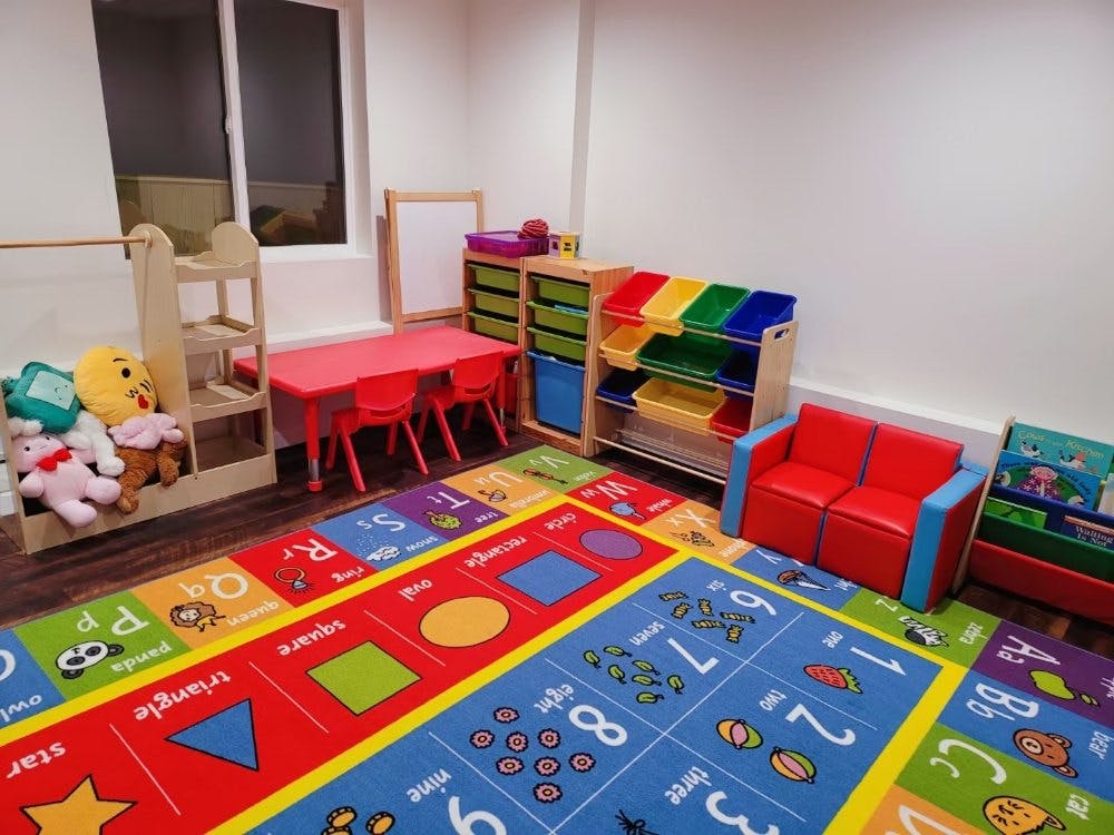 Children's play area with colorful rug, small table and chairs, and toy storage