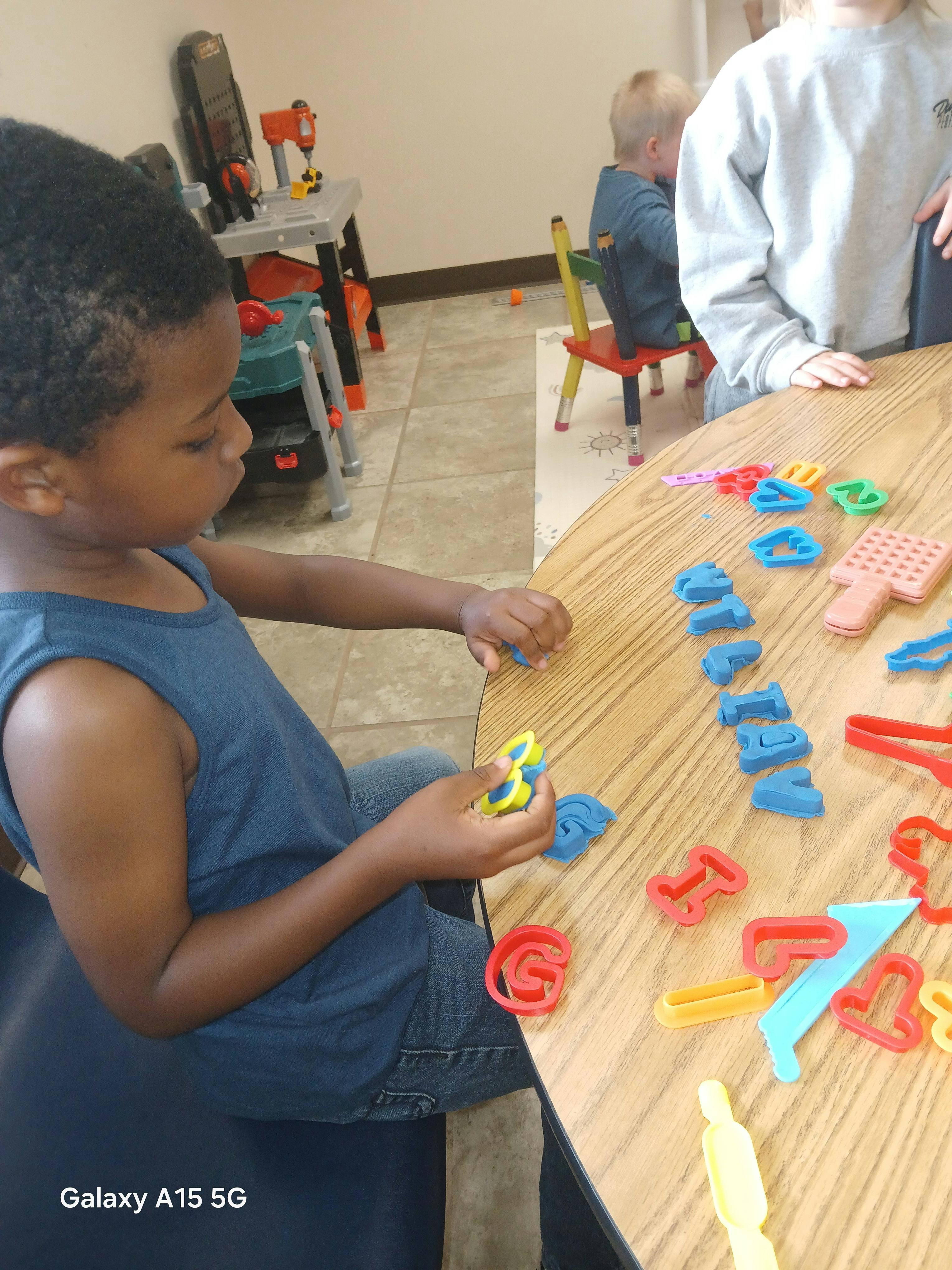 Child playing with colorful letter and shape cutouts on a wooden table