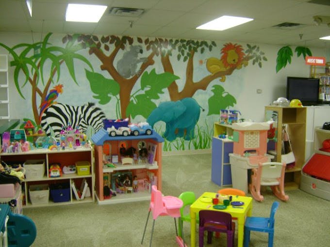 Playroom with jungle mural, toys, and small tables and chairs