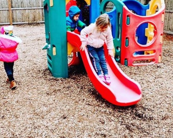 Child going down a red slide on a playground