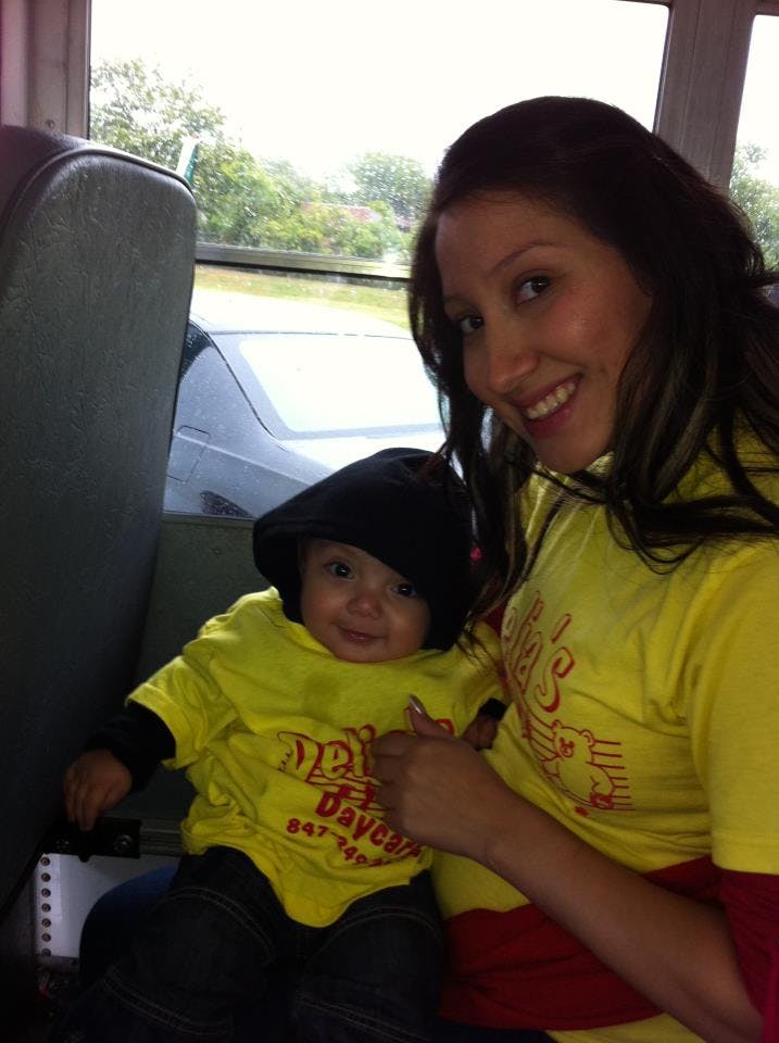Person holding a child wearing a black hat and yellow shirt