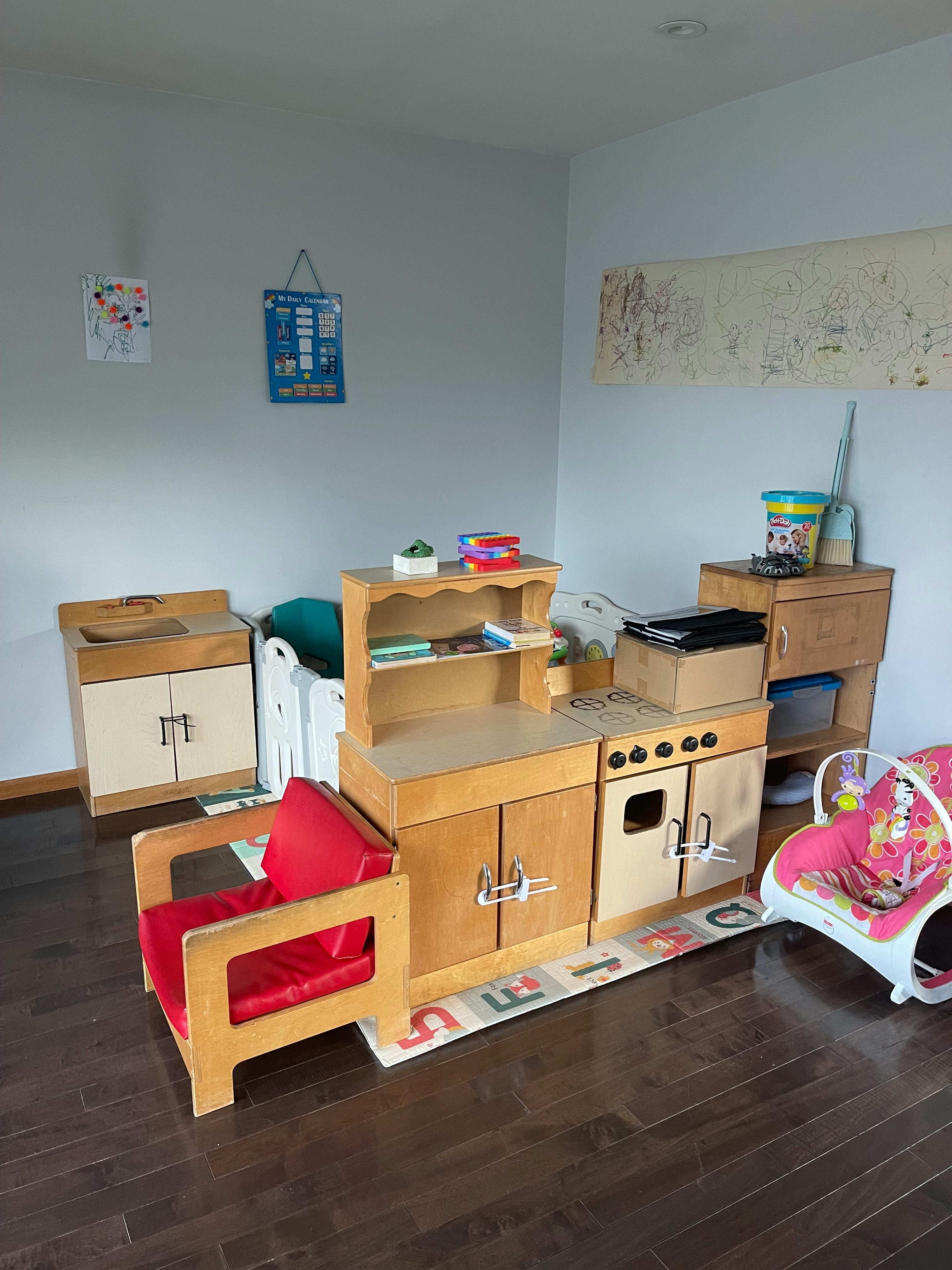 Child's play kitchen set with a red chair and baby bouncer